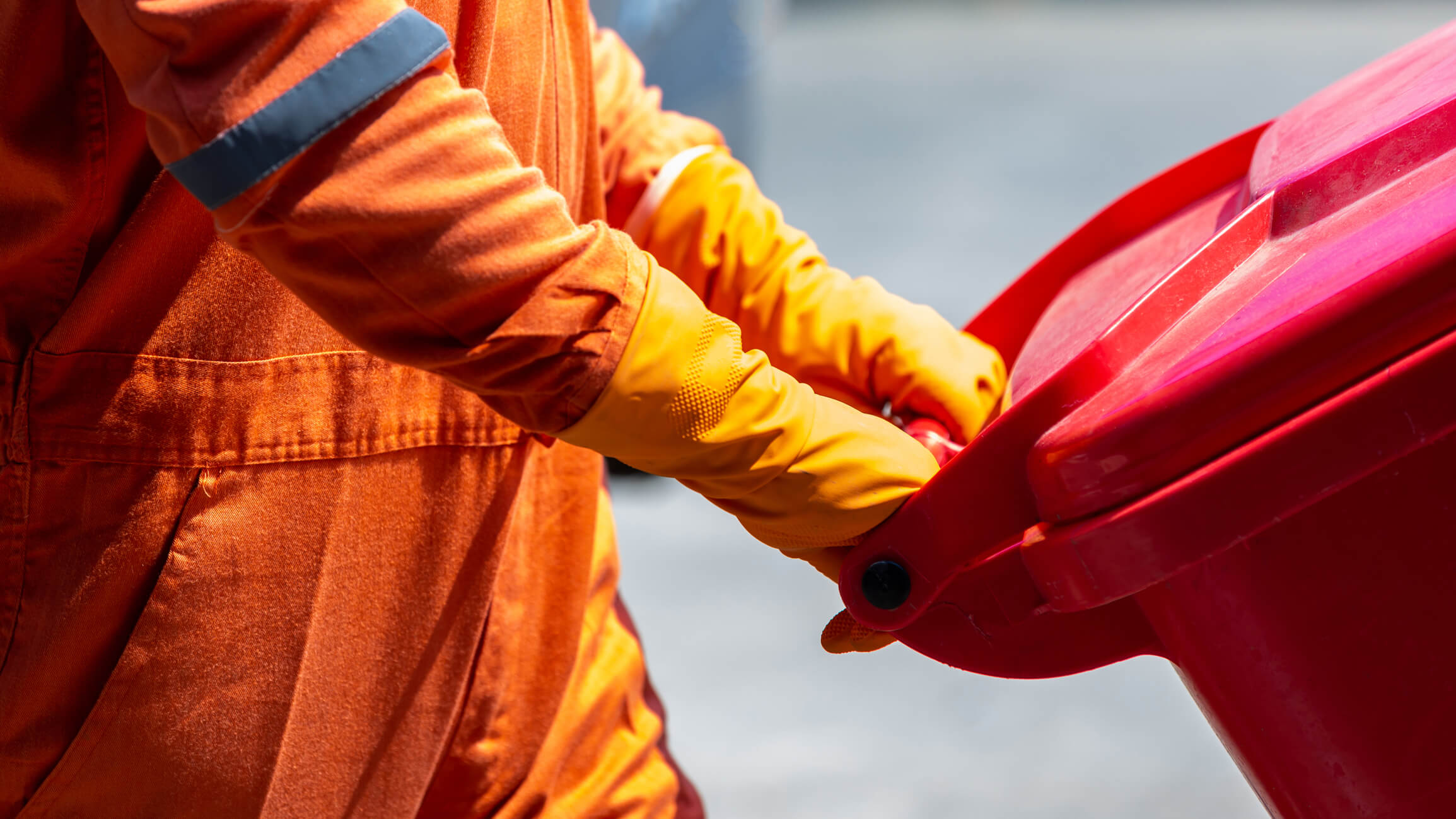 Man in PPE wheeling away disposable waste